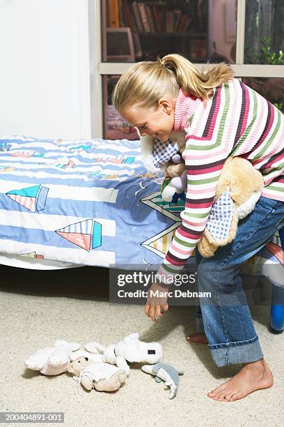 girl (10-12) picking up cuddly toys from bedroom floor, side view - välstädat rum bildbanksfoton och bilder