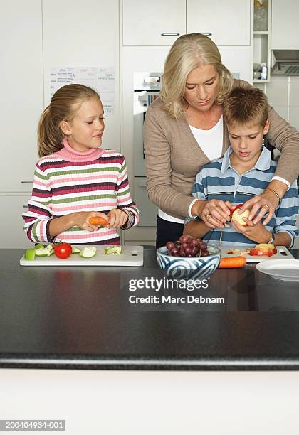 mädchen (10-12) vor mutter ihnen zwei bruder peel apple - mädchen 10 12 stock-fotos und bilder