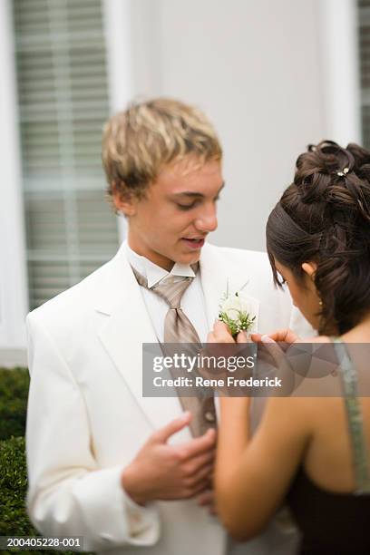 teenage girl (14-16) placing corsage on teenage boy (14-16) - pin up girl stockfoto's en -beelden