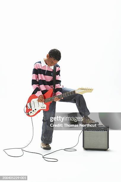 boy (9-11) playing electric guitar, resting foot on amplifier - amplifier fotografías e imágenes de stock