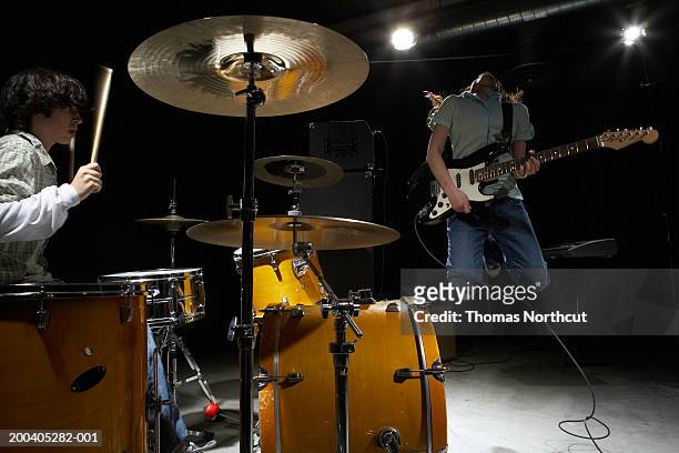 Teenage (14-16) band, boy playing drums, girl playing electric guitar