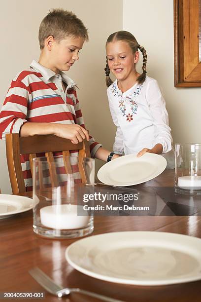 twin borther and sister (10-12) laying table, smiling - mädchen 10 12 stock-fotos und bilder