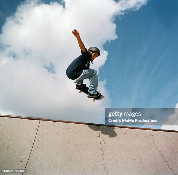 teenage male (14-16) skateboarder jumping on halfpipe, low angle view - skate imagens e fotografias de stock