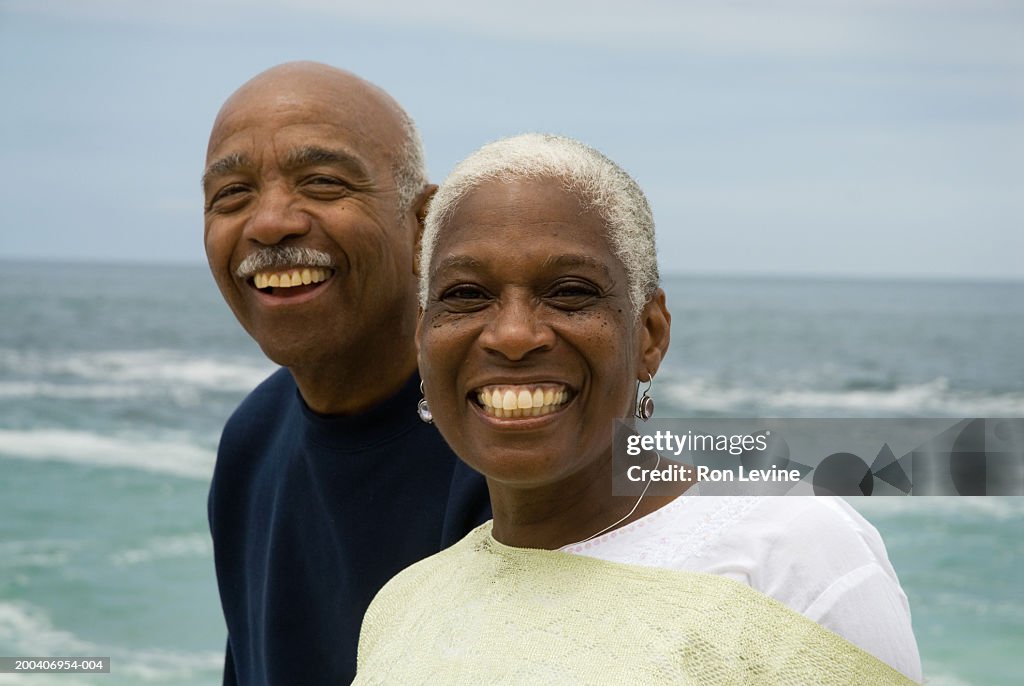 Senior couple smiling on beach, portrait, close-up