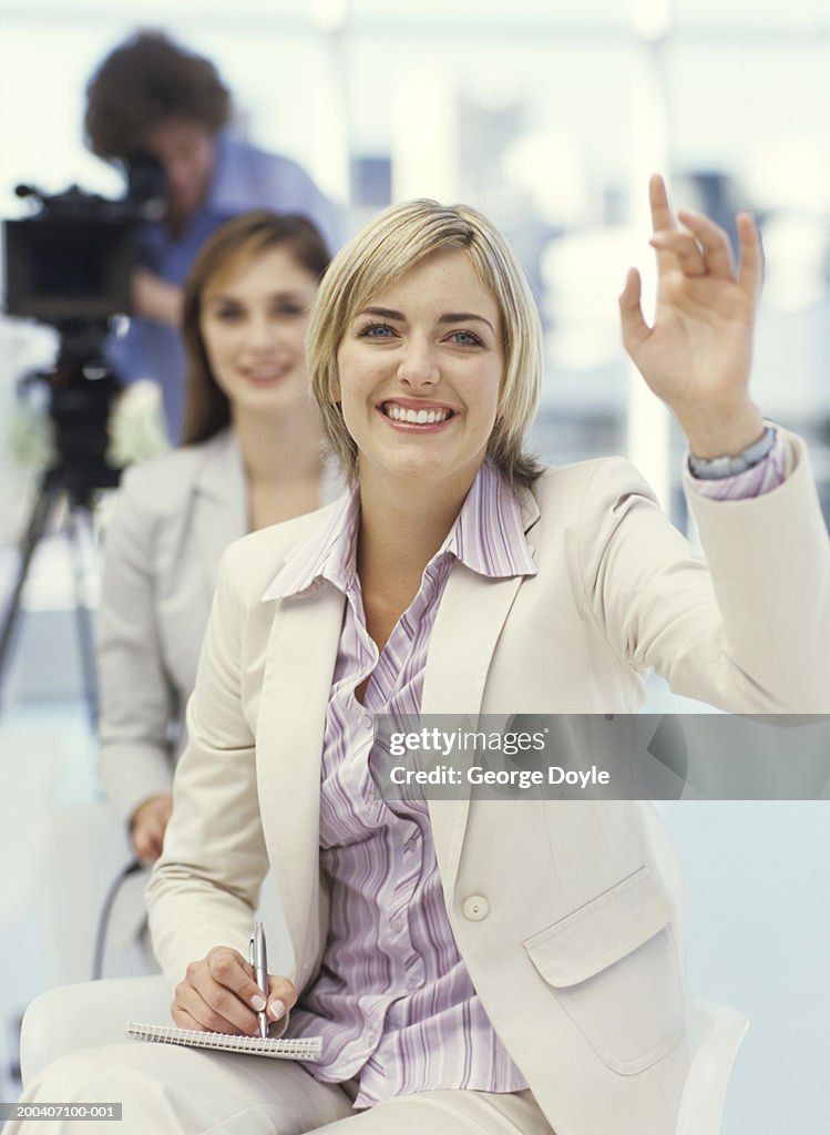 Young businesswomen making notes with hand up, smiling