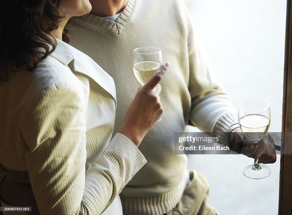 Mature couple holding wine glasses, mid section
