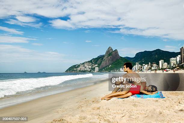 young  couple relaxing on blanket at beach, side view - ipanema beach stock pictures, royalty-free photos & images