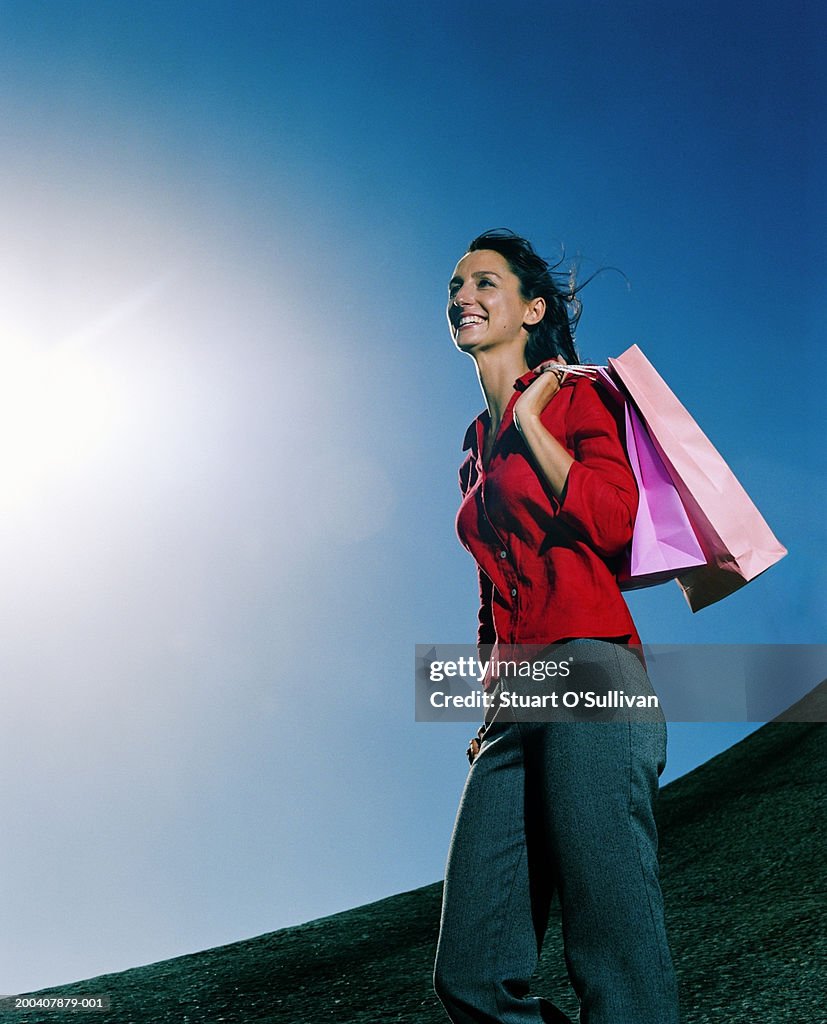 Young woman smiling, shopping bags over shoulder, low angle view