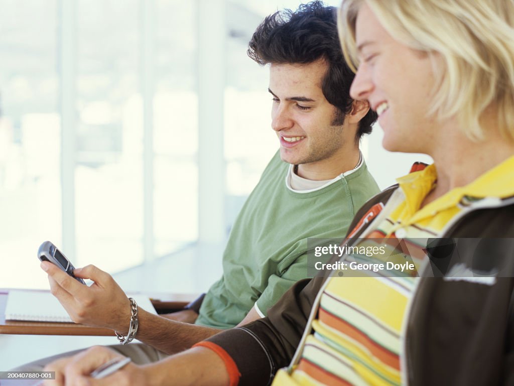 Two young men looking at mobile phone, smiling