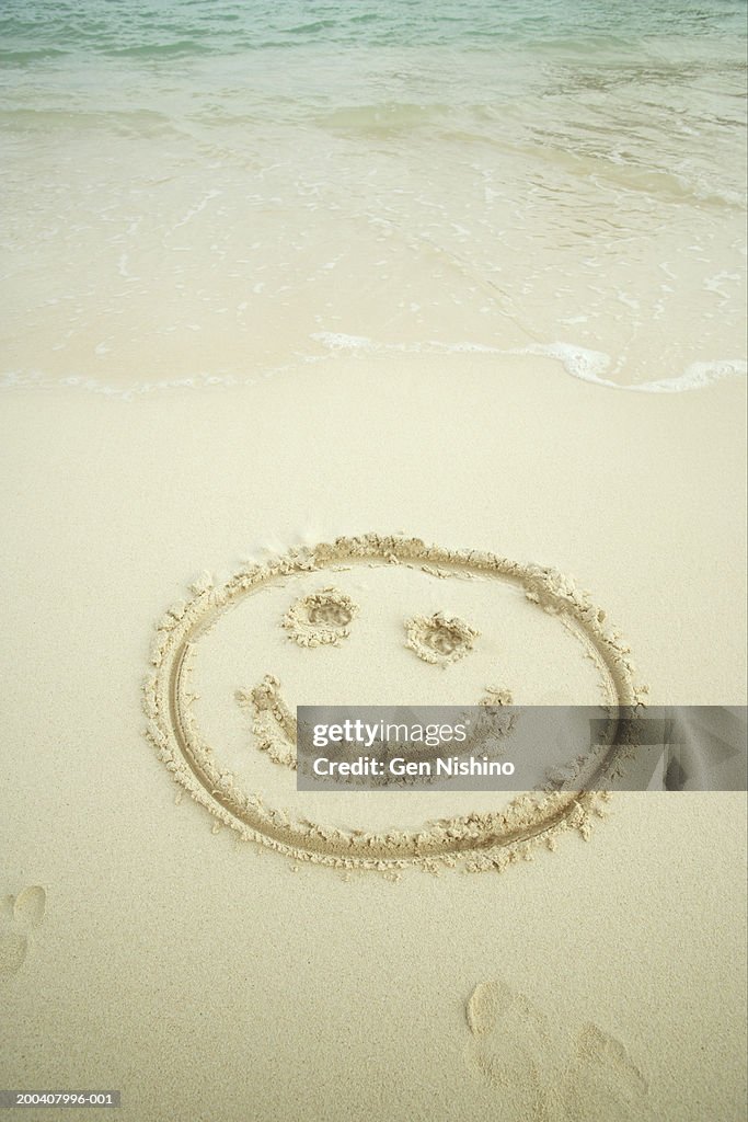 Smiling face drawn in sand
