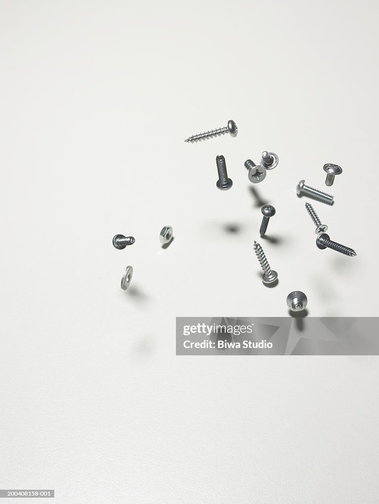 Screws, nuts and bolts bouncing on counter, close-up