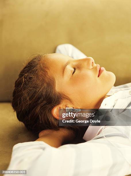 girl (9-11) lying on back listening to mp3, eyes closed, side view - lying on back girl on the sofa stock-fotos und bilder