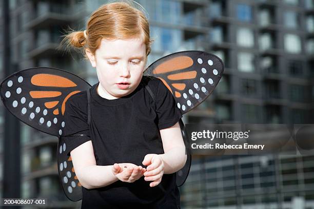 girl (5-7) with butterfly wings holding ladybug, looking down - costume wing stock pictures, royalty-free photos & images