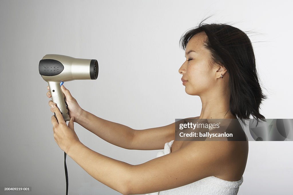 Woman blow drying hair in bath towel