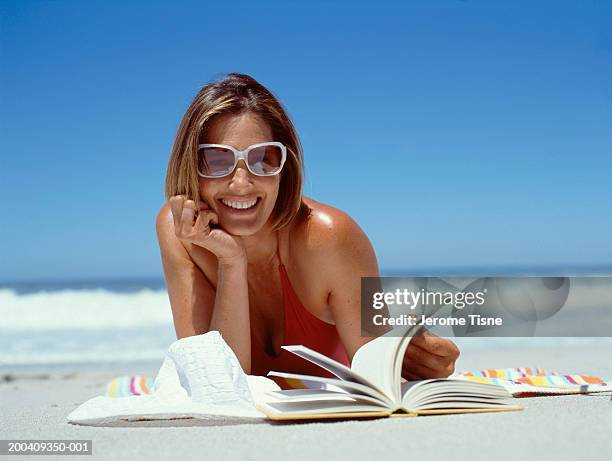 mature woman lying on beach with book, portrait - sunbathing stock pictures, royalty-free photos & images