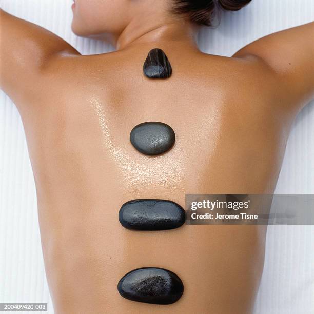 naked young woman receiving hot stone treatment, overhead view - human back stock pictures, royalty-free photos & images