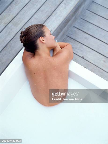young woman in milk bath, rear view, elevated view - milchbad stock-fotos und bilder