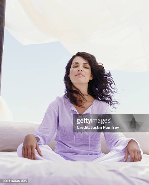 young woman sitting crossed legged, head back, eyes closed - budismo imagens e fotografias de stock