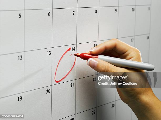 woman circling day on wall calendar, close-up - written date stock-fotos und bilder