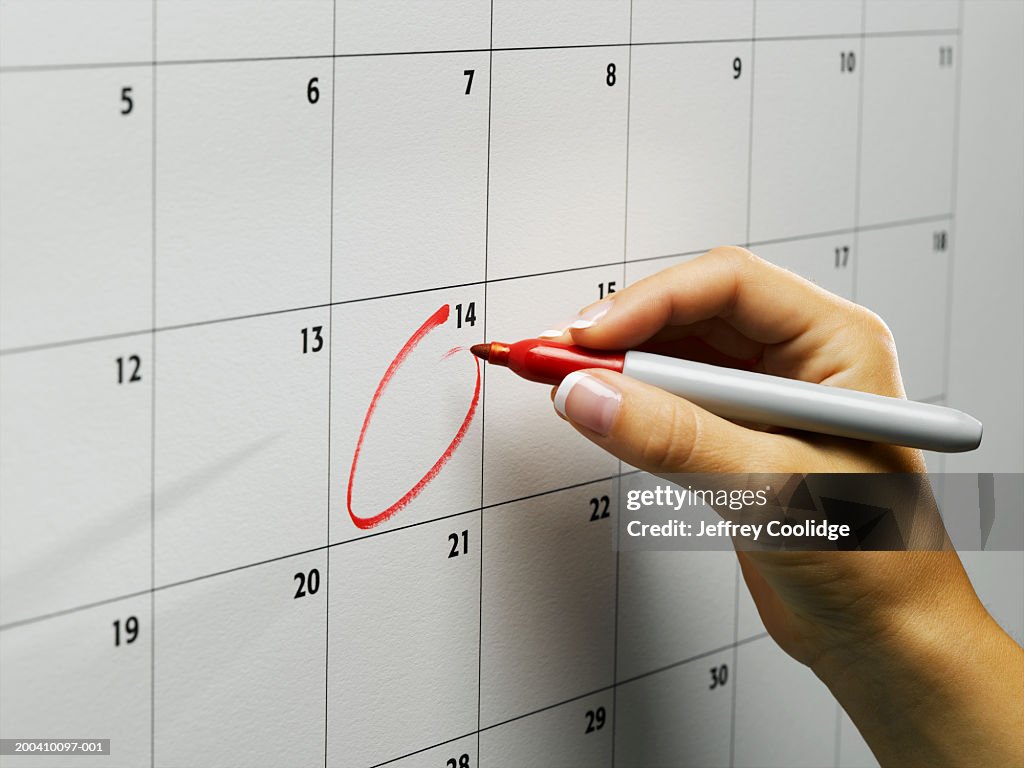 Woman circling day on wall calendar, close-up