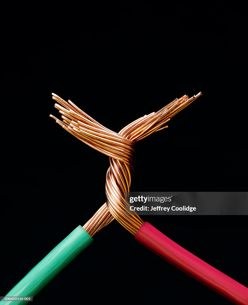 Two electrical cables with copper wires twisted together, close-up
