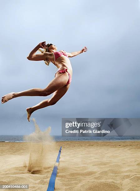 woman in volleyball spiking postion, side view - junge frau strand sand springen stock-fotos und bilder