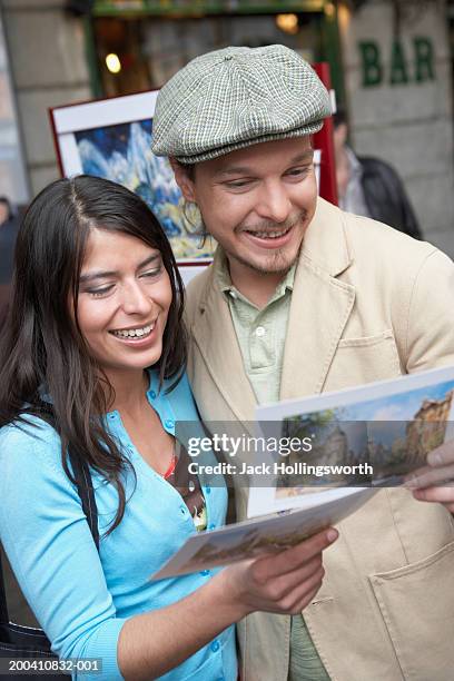 close-up of a young couple looking at postcards - gorra plana fotografías e imágenes de stock