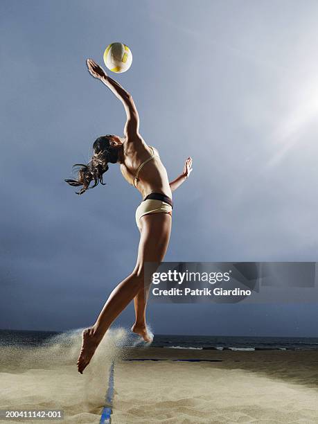 woman spiking volleyball on beach, side view - beach volleyball stock pictures, royalty-free photos & images