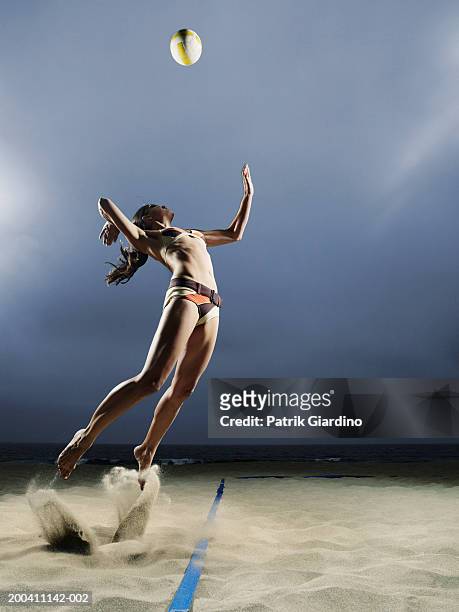 woman about to spike volleyball on beach, side view - beach volleyball spike stock pictures, royalty-free photos & images