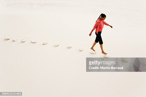 woman walking on stepping stones on white sandy beach, elevated view - stepping stone top view stock pictures, royalty-free photos & images