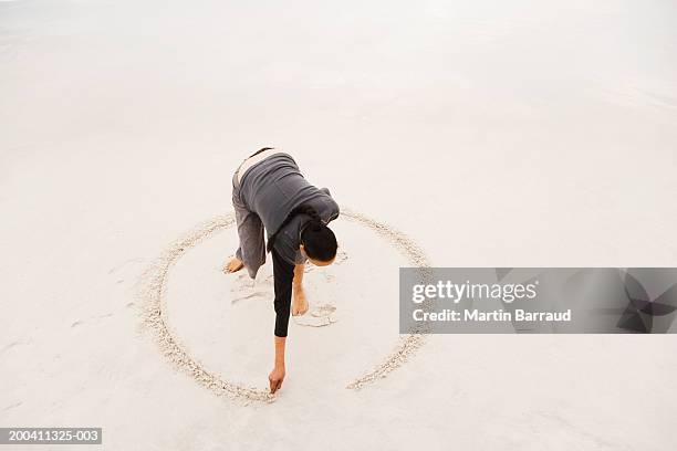 woman drawing circle in sand on beach, elevated view - woman bending over 個照片及圖片檔
