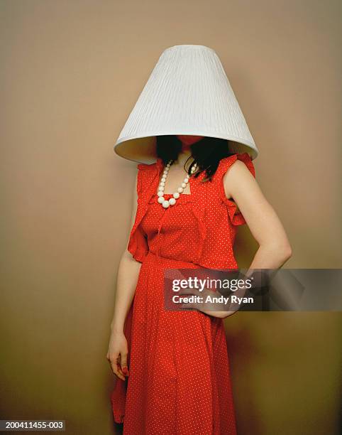 woman wearing red dress with lamp shade on head and hand on hip - lamp shade fotografías e imágenes de stock