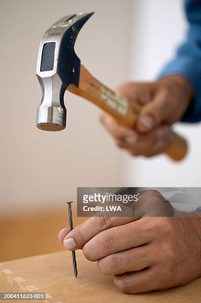 man hammering nail - hammer and nail fotografías e imágenes de stock