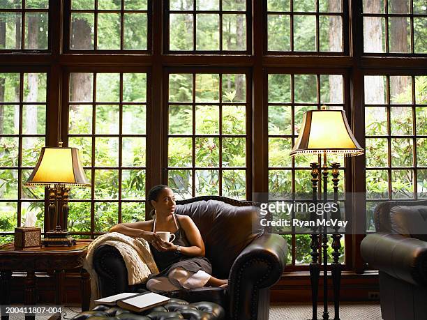 mature woman drinking coffee on leather armchair in lobby of lodge - hotel de lujo fotografías e imágenes de stock