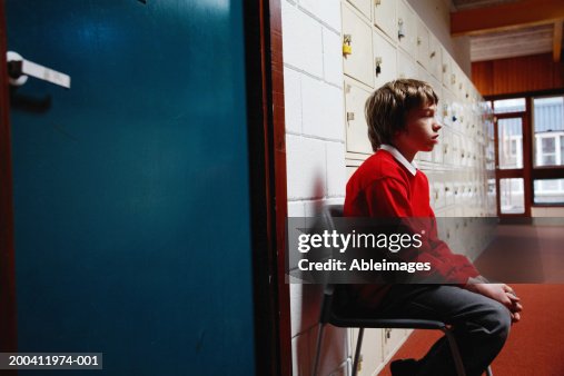 Schoolboy (11-13) sitting on chair in corridor, side view Schoolboy (11-13) sitting on chair in corridor, side view