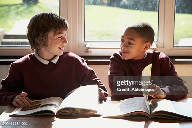dois schoolboys (9 a 12 anos) sentada em sala de aula e virando páginas dos livros, s - só meninos - fotografias e filmes do acervo
