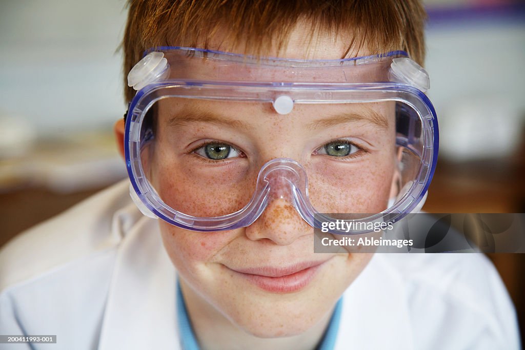 Schoolboy (11-13) wearing protective goggles, smiling, portrait