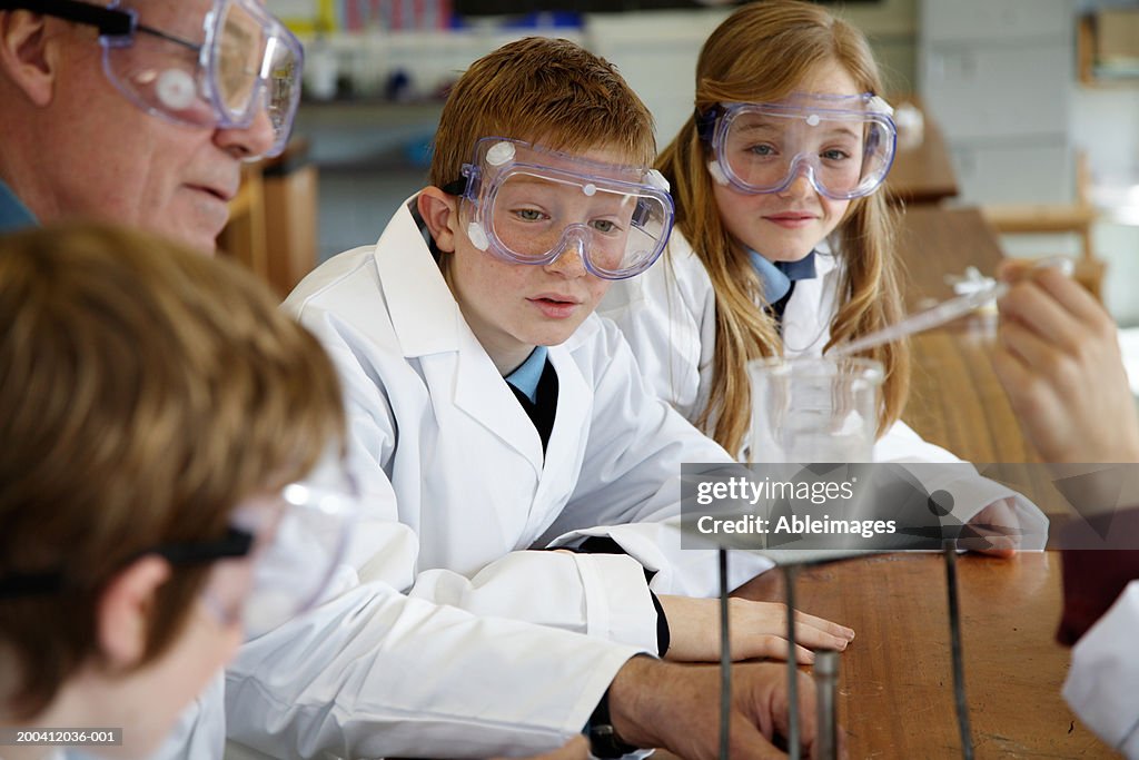 Pupils (11-13) and teacher watching experiment in science class