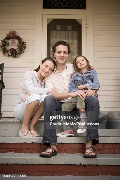 family sitting on steps in front of house, smiling, portrait - three people portrait stock pictures, royalty-free photos & images