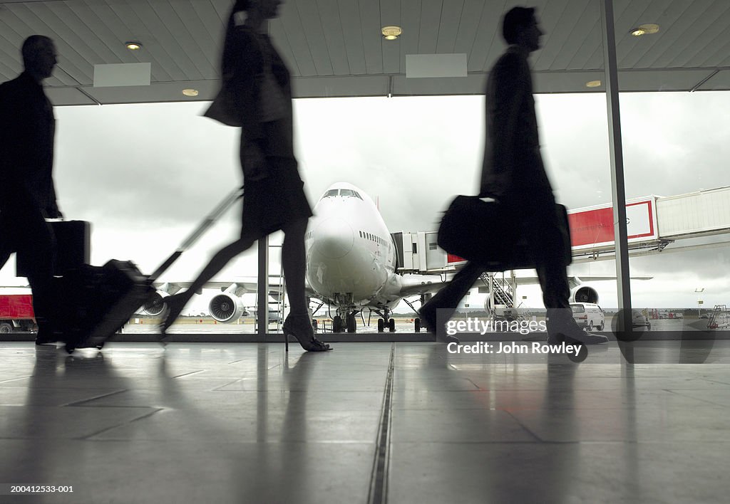 People walking through airport, silhouette (focus on aeroplane)
