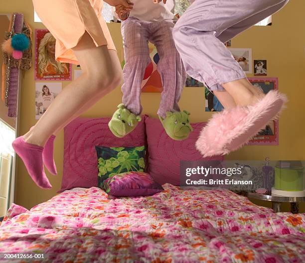 teenage girls (13-17) in nightwear jumping on bed, low section - girls sleepover stock-fotos und bilder