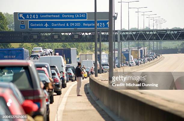 england, traffic jam on m25 motorway, man waiting outside car - traffic uk stock-fotos und bilder