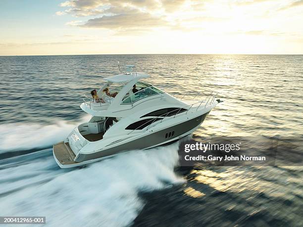 three people relaxing on cruiser power boat, side view - motorboat stock pictures, royalty-free photos & images