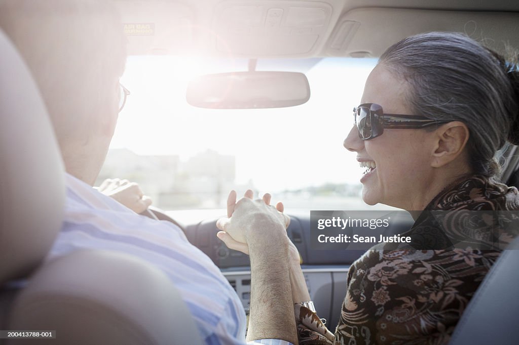 Mature couple holding hands in car, rear view, close-up