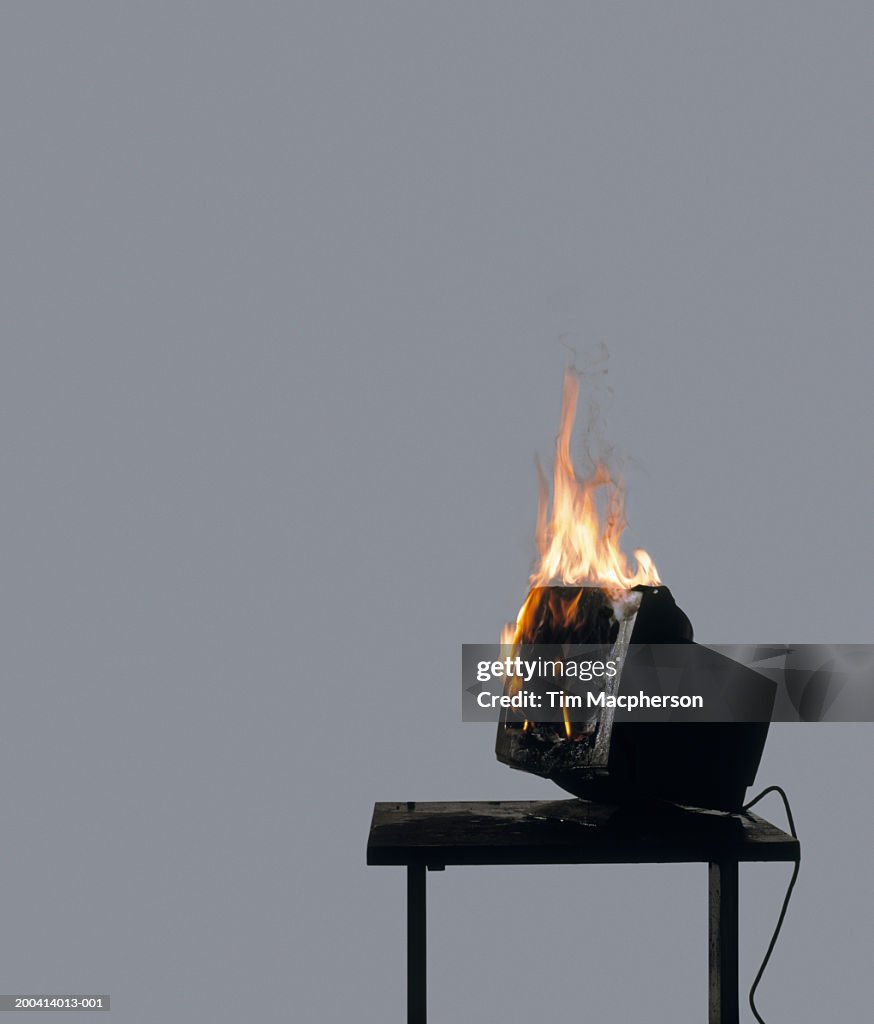 Computer terminal on fire on table (Digital Composite)