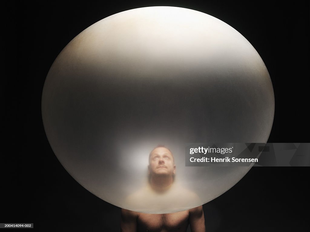 Man's head inside inflated balloon, looking up