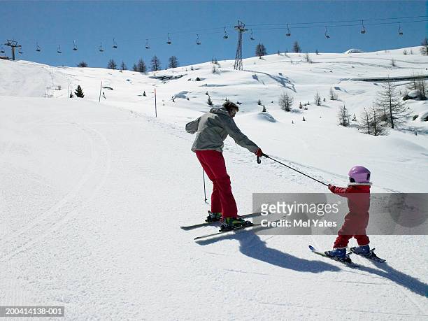 father skiing on slope towing daughter (3-6) with ski pole, rear view - ski pole stock-fotos und bilder