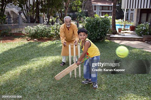 grandfather playing cricket with grandson (6-8) batting ball - sports india stock pictures, royalty-free photos & images