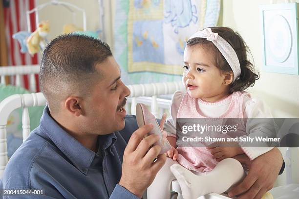 young father with baby girl (12-15 months), holding shoe - headband stock pictures, royalty-free photos & images