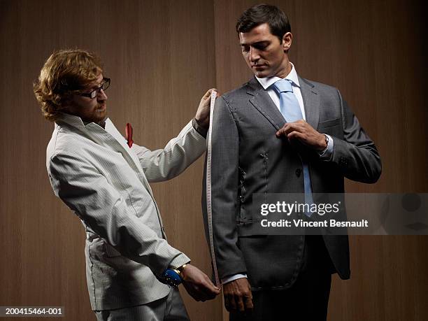 tailor measuring man in suit, low angle view - tailor stock pictures, royalty-free photos & images